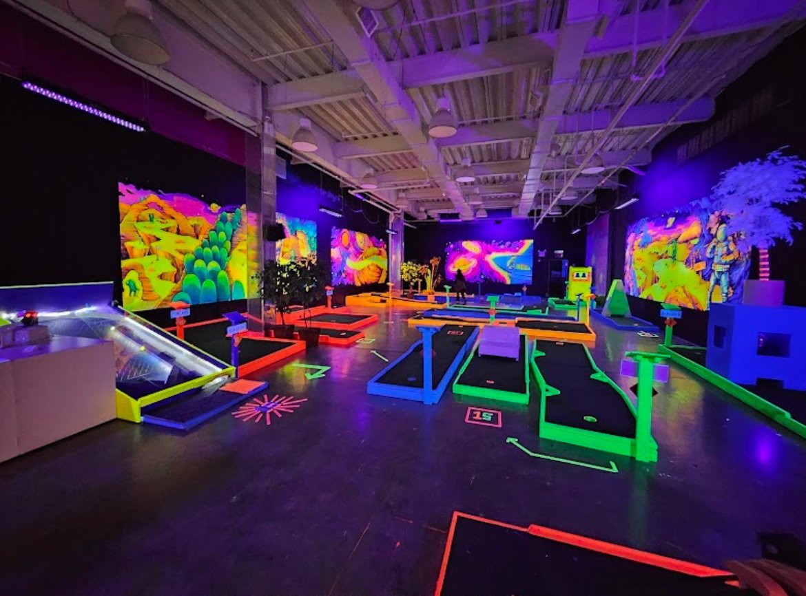 Interactive neon art gallery with glowing digital displays and colorful projections inside Planet X Mini Glow Golf